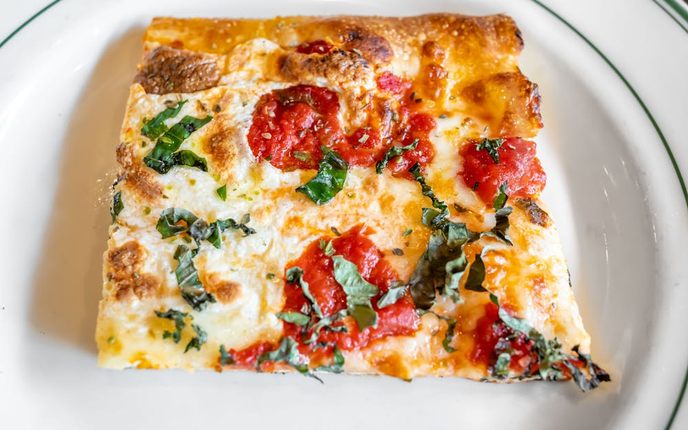 Square slice of Nonna Delia's pizza with tomato and basil