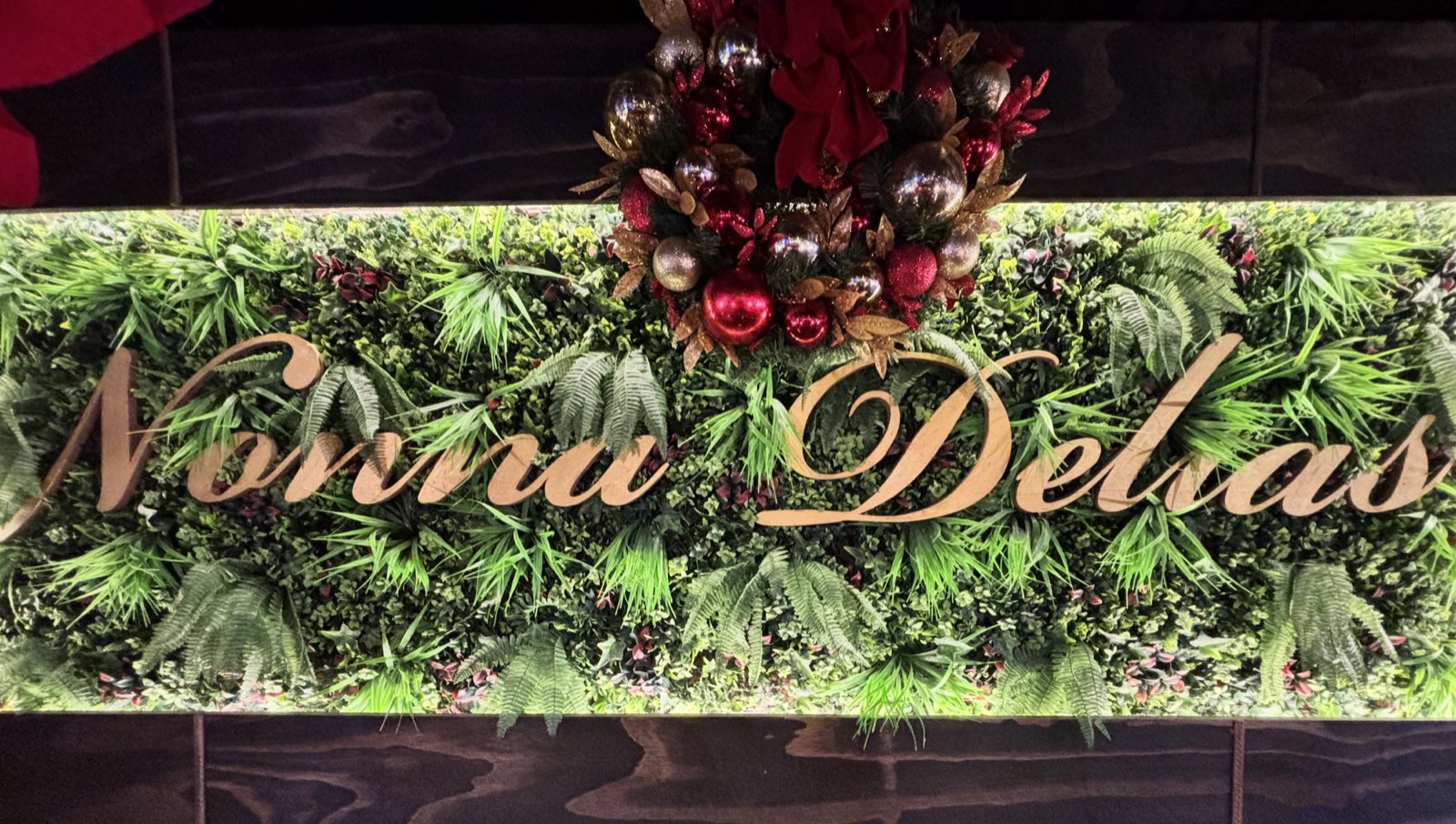 The Nonna Delia's sign on the restaurant's greenery wall